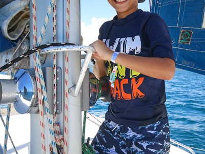 boy posing next to ropes on catamaran