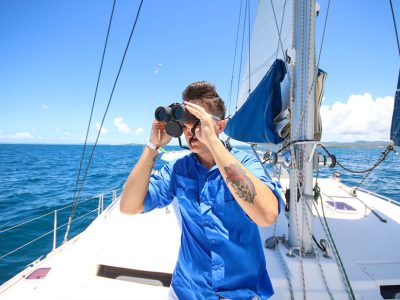 man looking through binoculars on boat